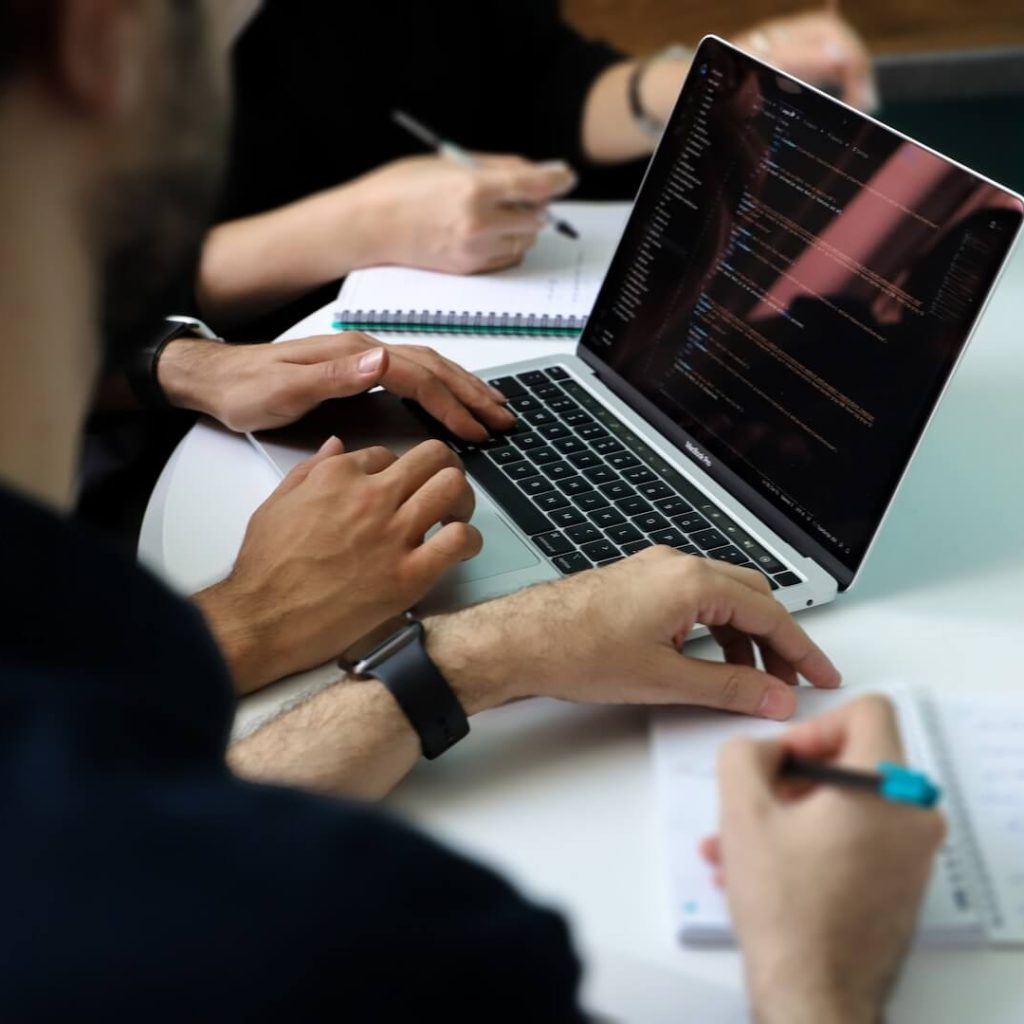 a group of people sitting around a laptop computer